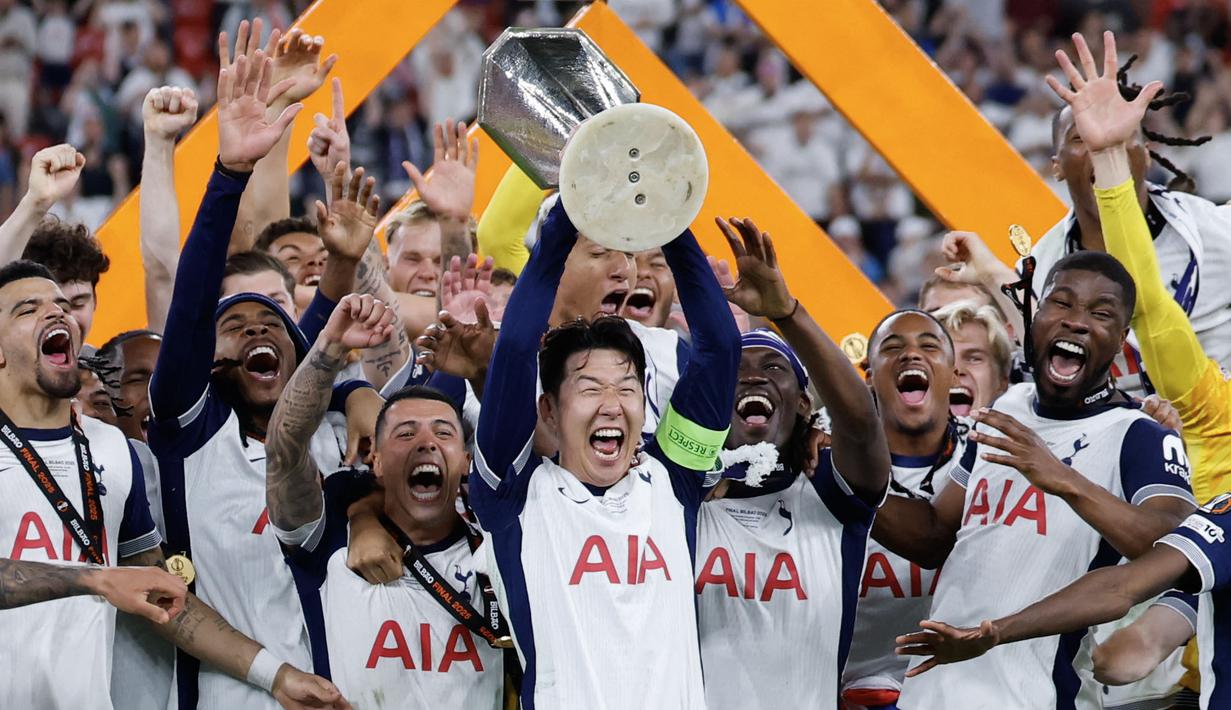Son Heung-min (tengah) mengangkat trofi bersama para pemain Tottenham setelah menjuarai final Liga Europa 2024/2025 di Stadion San Mames, Bilbao, Spanyol, Kamis (22/05/2025) WIB. Tottenham menang dengan skor 1-0 atas Manchester United. (AFP/Thomas Coex)