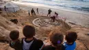 Karya seni tersebut merupakan bentuk ketahanan dan upaya untuk memberikan kegembiraan bagi warga Palestina yang terpaksa mengungsi akibat perang berkepanjangan antara Israel dan Hamas. Tampak dalam foto, anak-anak berdiri di atas bukit pasir di atas patung pasir dengan pesan ucapan "Selamat Datang, Ramadan" yang dibuat oleh seniman Palestina, Yazeed Abu Jarad, di sepanjang pantai di Khan Younis, selatan Gaza pada 17 Februari 2026. (Bashar Taleb/AFP)