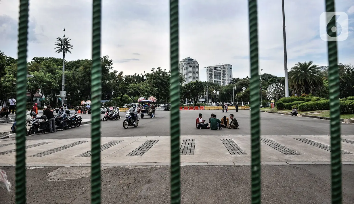 Warga menikmati sore hari di depan gerbang masuk Monumen Nasional (Monas), Jakarta, Minggu (15/11/2020). Meski masih ditutup untuk umum sejak awal pandemi Covid-19, kawasan Monas tetap ramai dikunjungi warga untuk sekadar mengisi akhir pekan. (merdeka.com/Iqbal S Nugroho)