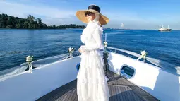 Gaya Syahrini saat berlayar pun begitu elegan. Wanita berusia 40 tahun itu mengenakan gaun putih panjang penuh renda. Sebagai pelengkap penampilannya, penyanyi yang pernah populer dengan 'jambul khatulistiwa' itu memakai topi bundar ala pantai dan kacamata hitam. (Liputan6.com/IG/@princessyahrini)