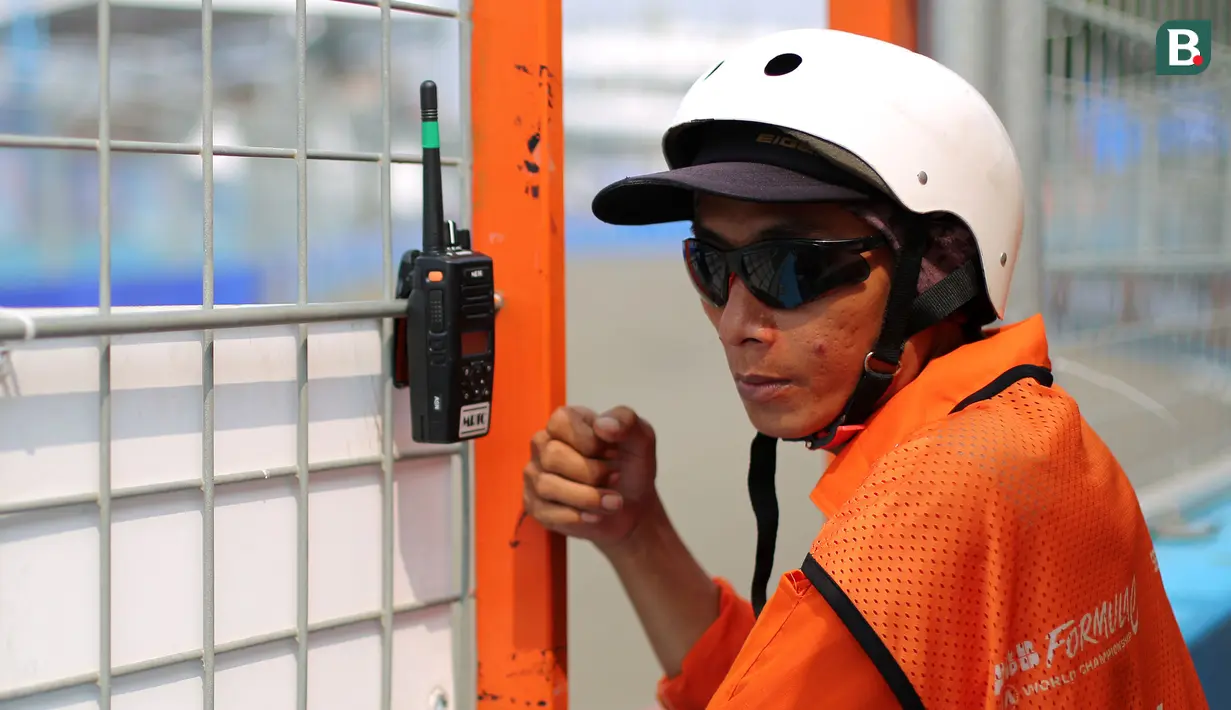 Seorang Marshall sedang mendengarkan komunikasi melalui Handy Talky (HT) menjelang balapan Jakarta E-Prix 2023 Round-11 yang berlangsung di Jakarta International E-Prix Circuit, Ancol, Jakarta, Minggu (04/06/2023). (Bola.com/Bagaskara Lazuardi)