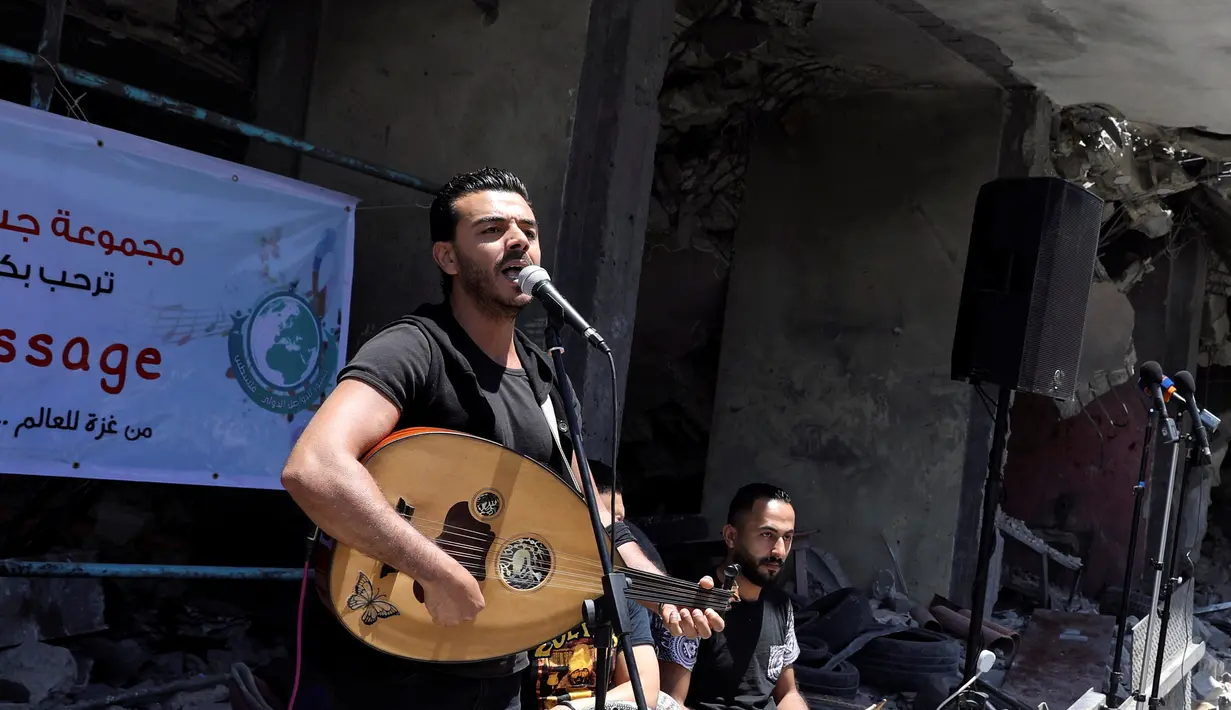 Penampilan seorang penyanyi Palestina selama acara musik di puing-puing bangunan yang baru-baru ini hancur oleh serangan udara Israel di kota Gaza, Selasa (14/5/2019). Aksi itu untuk menyerukan pemboikotan terhadap Kontes Lagu Eurovision 2019 yang diselenggarakan di Israel. (REUTERS/Mohammed Salem)