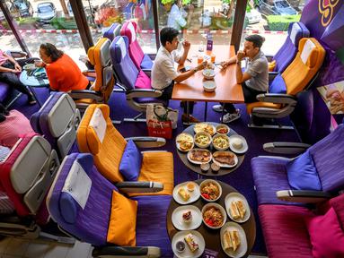 Orang-orang duduk di kursi pesawat saat makan di restoran pop-up bertema kabin pesawat di kantor pusat Thai Airways di Bangkok, 10 September 2020. Restoran pop-up ini menyajikan sekitar 2.000 makanan per hari untuk memulihkan pendapatan yang hilang selama pandemi virus corona. (Mladen ANTONOV/AFP)