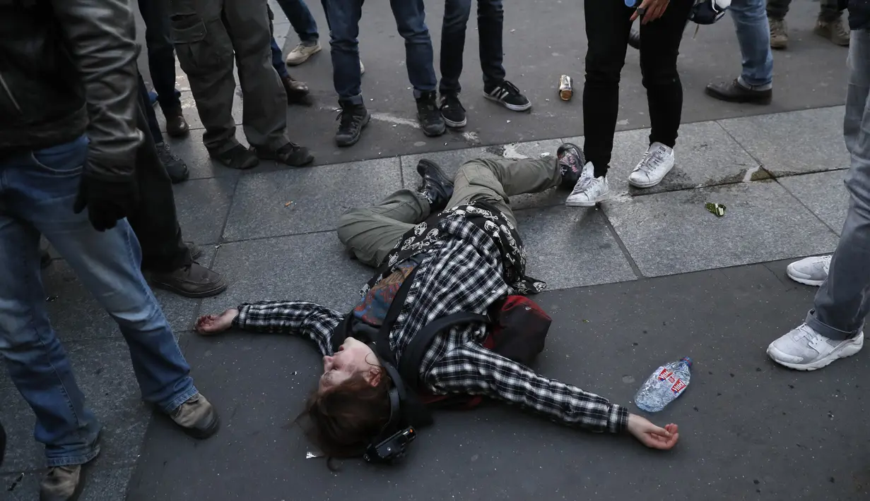 Seorang demonstran tergeletak di lapangan saat demonstrasi yang dilakukan oleh anti fasis usai pengumuman hasil putaran pertama pemilihan Presiden di Paris (23/4). Pengumuman hasil perolehan suara Pemilu tersebut menuai banyak protes. (AFP/Thomas Samson)