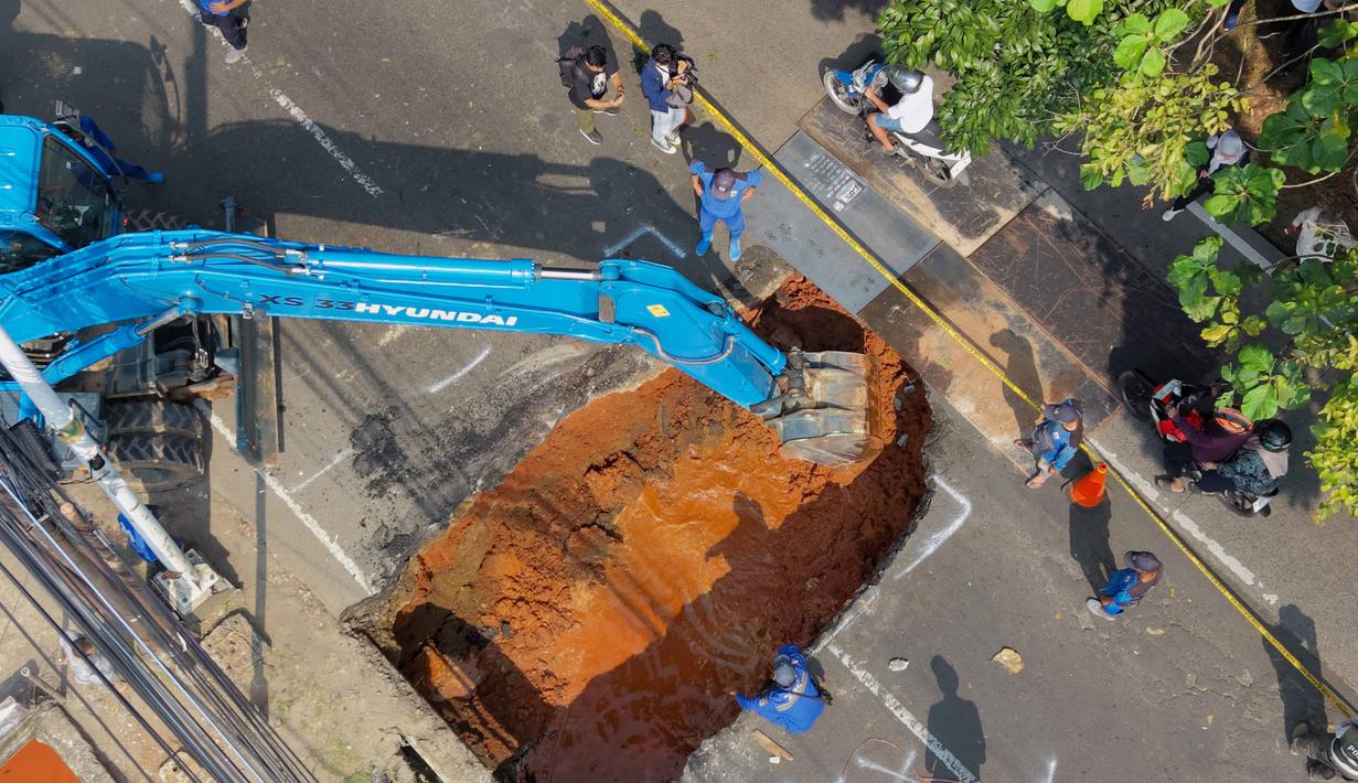 Foto udara menunjukkan aktivitas para pekerja menggunakan alat berat untuk membersihkan puing-puing dari lubang runtuhan yang terbentuk di Jalan Raya Lenteng Agung (arah Depok), Jakarta pada Jumat 29 Mei 2026. (BAY ISMOYO/AFP)