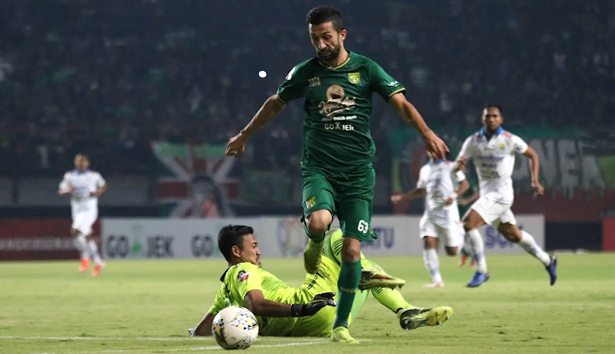 Striker Persebaya Surabaya, Manuchehr Jalilov, mengecoh kiper Persib Bandung, Deden Natshir, pada laga Liga 1 di Stadion Gelora Bung Tomo, Surabaya, Jumat (5/7). Persebaya menang 4-0 atas Persib. (Bola.com/Aditya Wani)