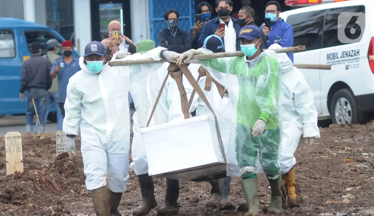 Petugas yang mengenakan APD membawa peti berisi jenazah dengan protokol COVID-19 di TPU Srengseng Sawah 2, Jakarta, Selasa (9/2/2021). Sudah lebih dari sepekan TPU Srengseng Sawah 2 menerima pemakaman korban COVID-19 dengan jumlah yang dimakamkan sehari maksimal 10 jenazah. (merdeka.com/Arie Basuki)