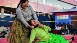 Pegulat Bolivia, Ana Luisa Yujra (kiri), bertarung dengan lawannya, Lidia Flores di atas ring gulat di El Alto, pada 24 November 2019. Di Bolivia ada sebuah atraksi gulat yang diperankan perempuan dengan menggunakan busana khas warga Bolivia. (Ronaldo SCHEMIDT / AFP)