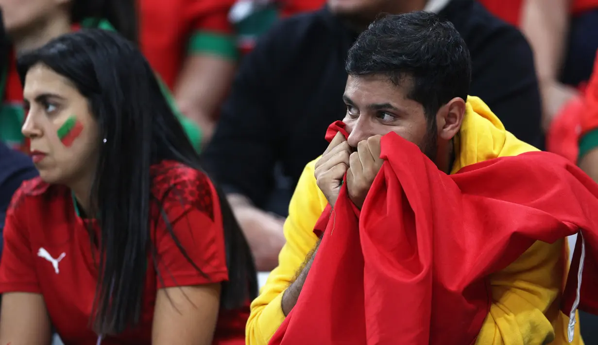 Reaksi suporter Maroko di akhir pertandingan setelah tim yang didukung kalah 0-2 dalam pertandingan sepak bola semifinal Piala Dunia Qatar 2022 antara Prancis dan Maroko di Stadion Al-Bayt di Al Khor, Doha, Qatar, Kamis (15/12/2022). Meski harus mengubur mimpi menjadi juara Piala Dunia 2022, Maroko tetap mengucap syukur dengan melakukan sujud syukur di lapangan setelah pertandingan usai. (ADRIAN DENNIS / AFP)
