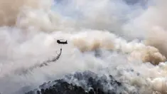 Sebuah helikopter militer menjatuhkan air di atas hutan dekat Desa Schinos, Korintus, Yunani, Kamis (20/5/2021). Kebakaran hutan besar di sebelah barat Athena merusak rumah-rumah dan mendorong evakuasi. (AP Photo/Petros Giannakouris)