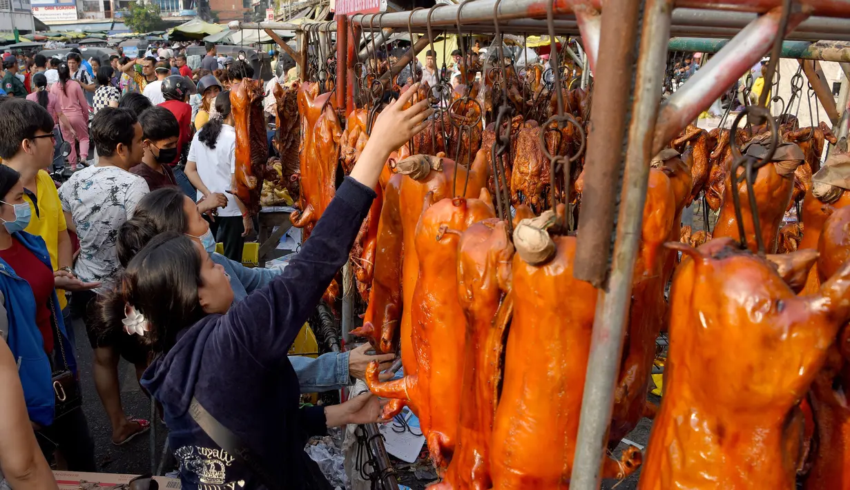 Seorang pedagang menggantung babi panggang di pasar di Phnom Penh, Kamboja (4/2). Menyambut Tahun Baru Imlek, warga Kamboja mempersiapkan daging babi panggang untuk sajian makan. (AFP Photo/Tang Chhin Sothy)