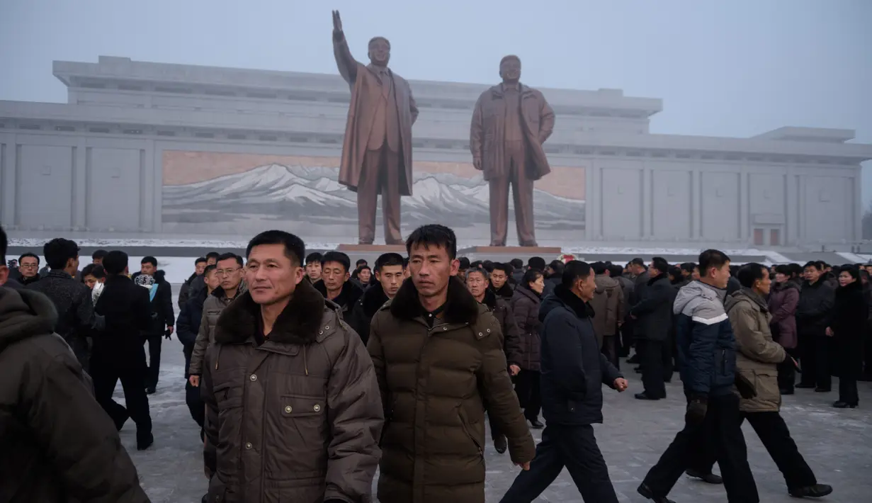 Penduduk Pyongyang usai memberi hormat untuk patung pemimpin Korea Utara Kim Il Sung dan Kim Jong Il selama Hari Peringatan Nasional di Bukit Mansu, Pyongyang (17/12).  Korea Utara tengah memperingati 7 tahun wafatnya  Kim Jong Il. (AFP Photo/Kim Won Jin)