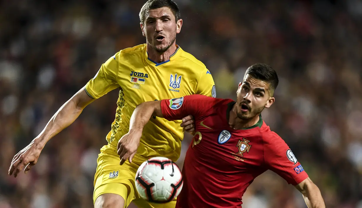 Striker Portugal, Andre Silva, berusaha melewati bek Ukraina, Sergii Kryvtsov, pada laga Kualifikasi Piala Eropa 2020 di Stadion Luz, Lisbon, Jumat (22/3). Kedua negara bermain imbang 0-0. (AFP/Patricia De Melo Moreira)