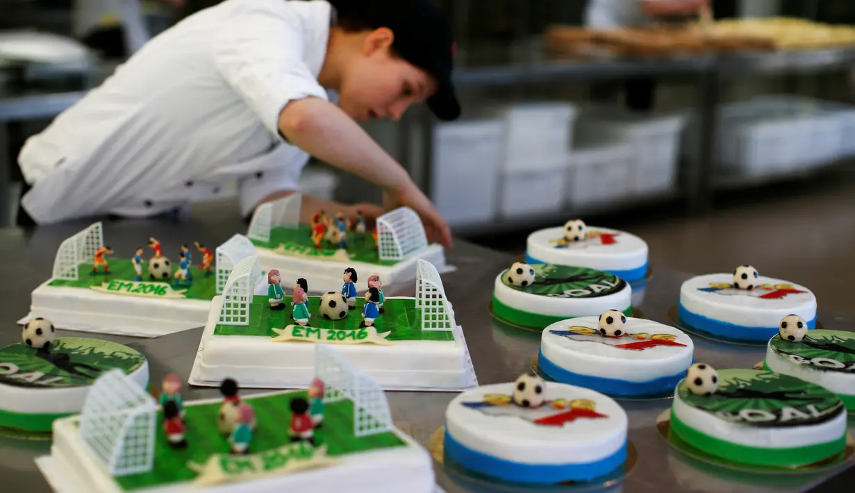 Pembuat kue menyelesaikan tahapan akhir pembuatan beragam kue bertema Euro 2016 yang dibuat di sebuah tempat pembuatan kue di Munich, Jerman, Senin (20/6). Beraneka kue bertema Euro 2016 mewarnai perhelatan sepakbola Eropa. (REUTERS/Michaela Rehle)