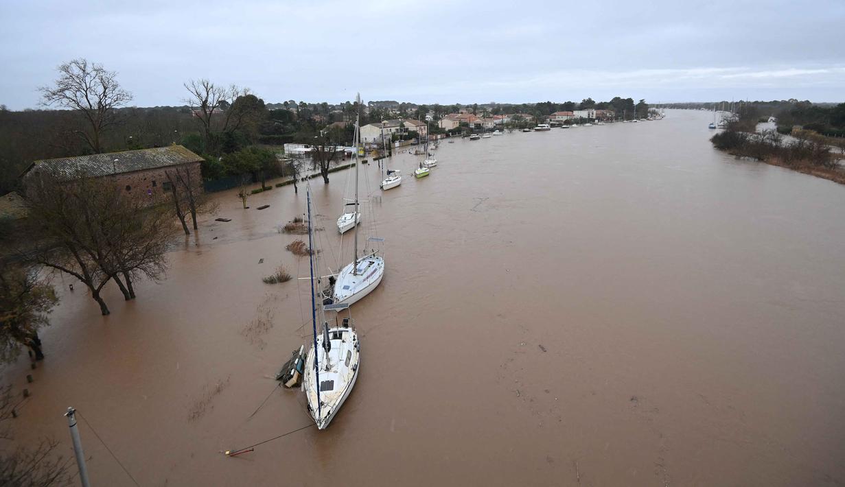 Banyak jalan di sekitar Agde dan komune Laroque terputus atau sulit dilalui karena arus sungai yang deras. Tampak foto yang menunjukkan pemandangan umum Sungai Herault yang meluap setelah hujan lebat di Agde, Prancis selatan pada Selasa 23 Desember 2025. (Sylvain THOMAS/AFP)
