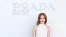 Sadie Sink mengenakan dress halter midi putih, dipadukan tas Prada putih dan heels runcing hitam bertali metalik [dok. Prada]
