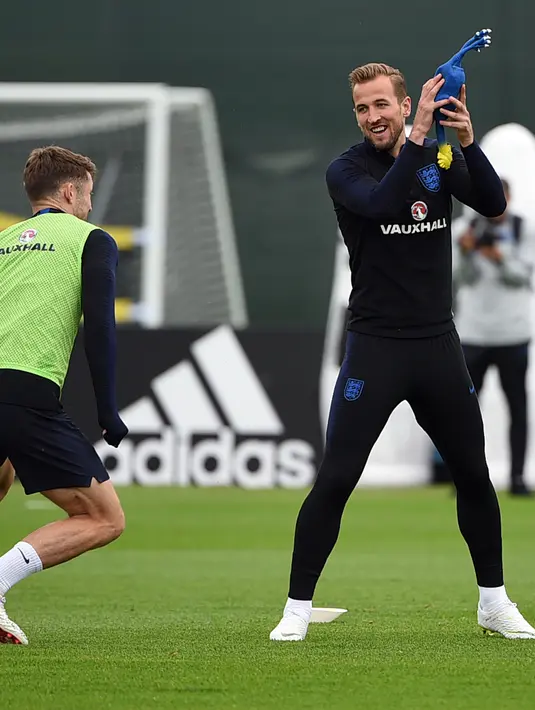 Penyerang Inggris Harry Kane (tengah) memegang mainan ayam selama mengikuti sesi latihan di Repino (10/7). Inggris akan bertanding melawan Kroasia pada babak semifinal Piala Dunia 2018. (AFP Photo/Ellis)