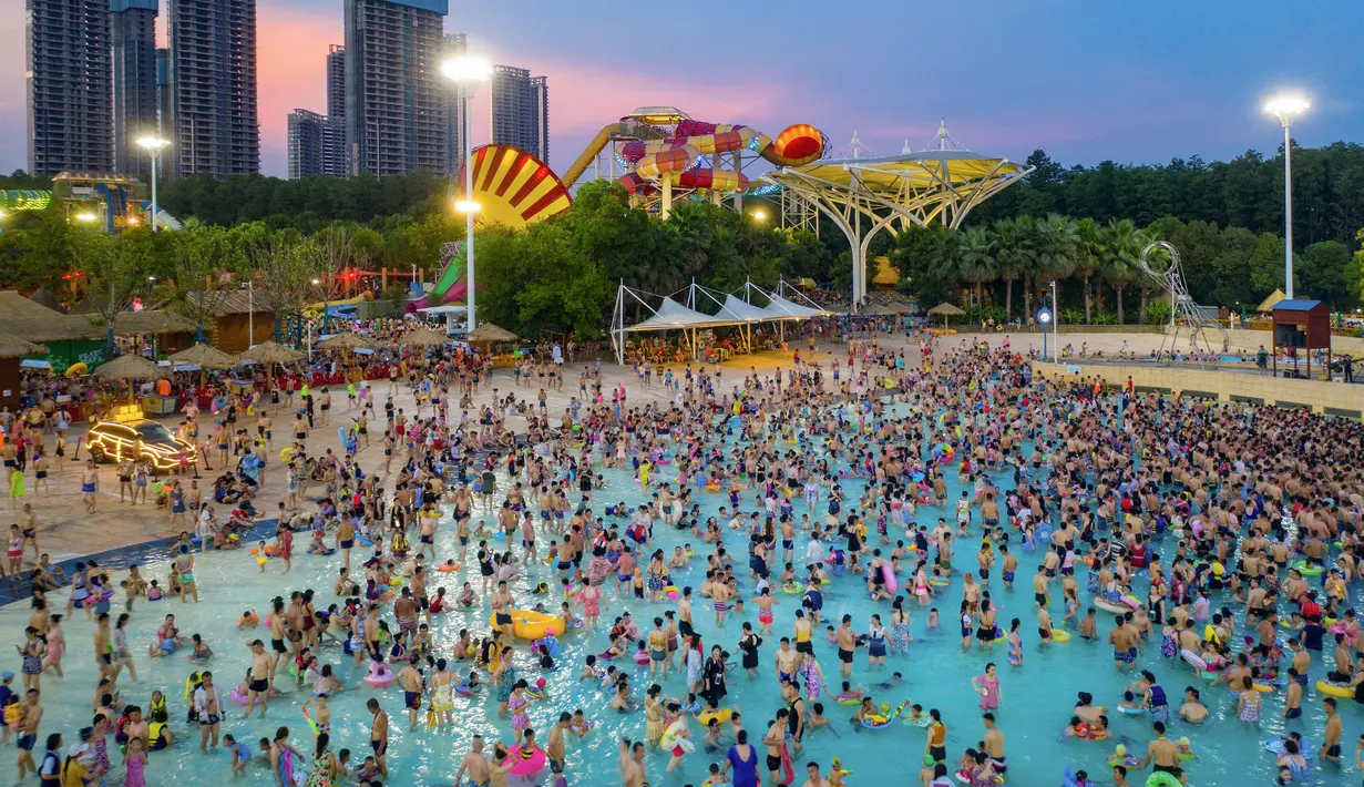Pengunjung bersantai sambil mendinginkan diri di kolam renang di Wuhan rovinsi Hubei, China pada 27 Juli 2019. Cuaca yang cukup panas membuat mereka berbondong-bondong menyesaki kolam renang. (Photo by - / AFP)