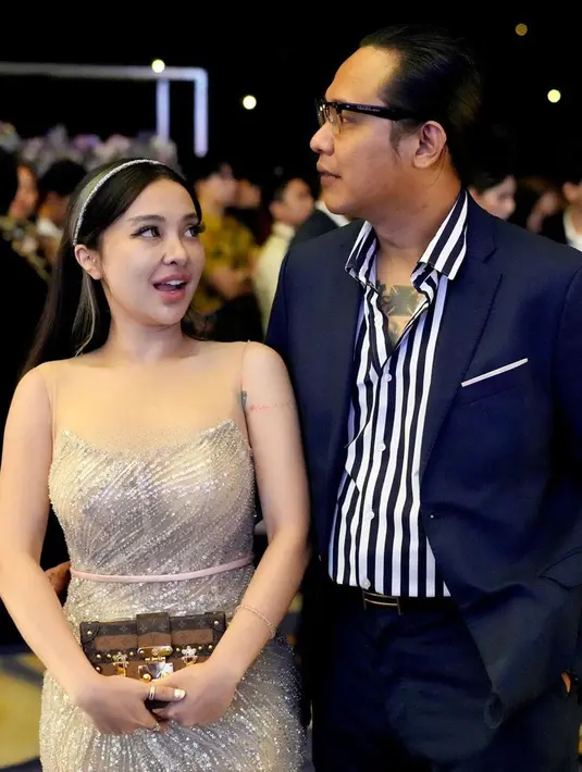 Gofar dan Cupi tampak begitu mesra saat hadir di pernikahan Rizky Febian. Keduanya juga terpantau berinteraksi manis. Seperti yang terlihat dalam salah satu foto unggahan, di mana mereka saling bergandengan tangan. Di momen ini, penampilan Cupi yang seksi dipuji anggun dalam balutan busana yang elegan. (Liputan6.com/IG/@pergijauh)