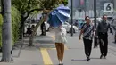 Seorang wanita merapikan payung selama gelombang panas di Jakarta, Selasa (22/10/2019).  BMKG memprediksi wilayah Indonesia akan mengalami panas selama kurang lebih satu minggu ini. Hal ini dikarenakan matahari yang berada dekat dengan jalur khatulistiwa. (Liputan6.com/Faizal Fanani)