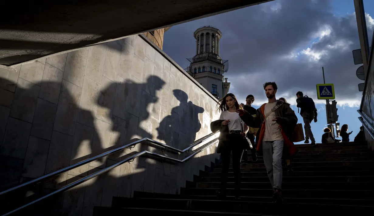 Orang-orang berjalan ke underpass di bawah jalan saat matahari terbenam di Moskow, Rusia, Selasa (15/9/2020). (AP Photo / Alexander Zemlianichenko)