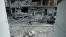 Seorang pria berjalan di antara kehancuran parah akibat  serangan udara rezim pemerintah Suriah di Ghouta Timur, Minggu (25/2). Sekjen PBB António Guterres menggambarkan kondisi di Ghouta timur saat ini sebagai "neraka di bumi". (HAMZA AL-AJWEH/AFP)