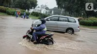 Kendaraan bermotor melintasi genangan air di Jalan Medan  Merdeka Barat, Jakarta, Kamis (24/1/2020). Hujan deras yang mengguyur Jakarta sejak pagi tadi mengakibatkan genangan air di Jalan Medan Merdeka Barat. (Liputan6.com/Faizal Fanani)