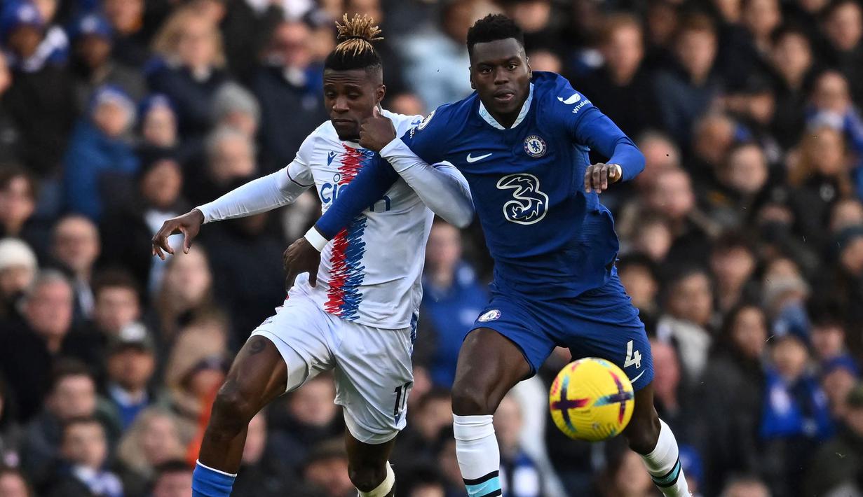 Pemain Chelsea, Benoit Badiashile (kanan) berebut bola dengan pemain Crystal Palace, Wilfried Zaha pada laga lanjutan Liga Inggris 2022/2023 di Stamford Bridge, London, 15 January 2023. Pemain berkebangsaan Prancis itu diboyong dari AS Monaco dengan harga 38 juta euro pada bursa transfer Januari 2023. (AFP/Ben Stansall)