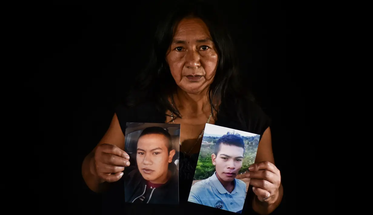 Lucila Huila, ibu dua dari enam pria Kolombia yang dibantai oleh terduga kelompok bersenjata pada 21 Agustus di El Tambo, berpose dengan foto putranya Heine Collazos, 25, dan Esneider Collazos, 23, di Popayan pada 28 Agustus 2020. Pembunuhan kembali berdarah di pedesaan Kolombia. (Luis ROBAYO/AFP)