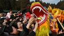 Orang-orang mencoba menyentuh seekor naga saat pertunjukan di sebuah kuil pada hari kedua Tahun Baru Imlek Naga di Beijing pada 11 Februari 2024. (GREG BAKER/AFP)