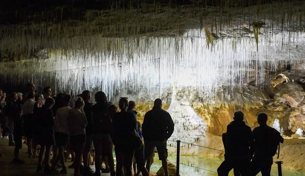 Pengunjung melihat es di dalam gua alam Choranche, di wilayah Vercors dekat Grenoble, Prancis (3/8). Sejak dimulainya gelombang panas, telah terjadi peningkatan setidaknya 10 persen jumlah pengunjung gua. (AFP Photo/Jean-Pierre Clatot)