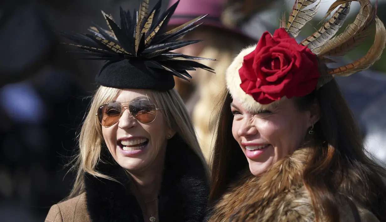 Dua wanita tersenyum saat tiba untuk hari pertama Festival Cheltenham di Cheltenham Racecourse, Inggris, Selasa (15/3/2022). Cheltenham adalah pertemuan berbasis pacuan kuda dalam kalender balap Perburuan Nasional di Inggris Raya. (Mike Egerton/PA via AP)