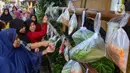 Warga memilih sayur dan pakaian bekas saat bazar sayuran, bahan makanan dan pakaian layak pakai gratis di Jalan Jati Padang VI, Pasar Minggu, Jakarta, Jumat (29/3/2024). (merdeka.com/Arie Basuki)