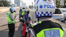 Petugas kepolisian memberikan surat tilang kepada pengendara sepeda motor  yang melintasi JLNT Kampung Melayu-Tanah Abang, Jakarta, Selasa (25/7). Sepeda motor dilarang melintas di JLNT tersebut karena merupakan jalur cepat. (Liputan6.com/Faizal Fanani)
