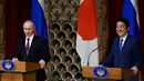 Presiden Rusia Vladimir Putin (Kiri) dan PM Jepang Shinzo Abe menggelar konferensi pers di Tokyo, Jepang, Jumat (16/12). Selain membahas soal wilayah sengketa, kedua belah pihak juga membahas situasi di semenanjung Korea. (REUTERS / Franck Robichon)