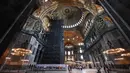 Turis mengunjungi bagian dalam Hagia Sophia di Istanbul, Turki pada 10 Juli 2020. Bangunan ini ini memiliki gaya arsitektur dari gabungan kontras dua agama, yakni arsitektur Kristen dan arsitektur Islam. (Ozan KOSE/AFP)