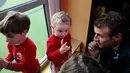 Presiden Prancis Emmanuel Macron menyimak pembicaraan anak-anak saat mengunjungi Graffiti's- Association Le Moulin Vert di Normandia, Prancis (5/4). (AP / Christophe Ena, Pool)
