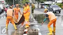 Semangat petugas membersihkan genangan air di Harmoni, Jakarta, Selasa (9/2). Buruknya sistem drainase membuat petugas terpaksa harus membersihkan genangan setiap kali hujan, meski dengan peralatan seadanya. (Liputan6.com/Immanuel Antonius)