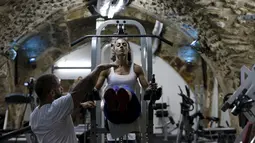 Binaragawan Anoush Belian saat berlatih dengan pelatihnya di tempat gym, Yerusalem (20/8/2015). Belian merupakan binaragawati pertama Palestina yang akan mengikuti kompetisi di Israel. (REUTERS/Ammar Awad)