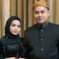 Putri Isnari membagikan potret terbarunya bareng suami ketika menghadiri prosesi siraman sekaligus mappaci calon suami Nia LIDA. Dalam momen bahagia tersebut, Putri tampil kompak dengan Abdul Azis mengenakan busana adat Jawa bernuansa hitam. (Liputan6.com/IG/@putriisnari3)
