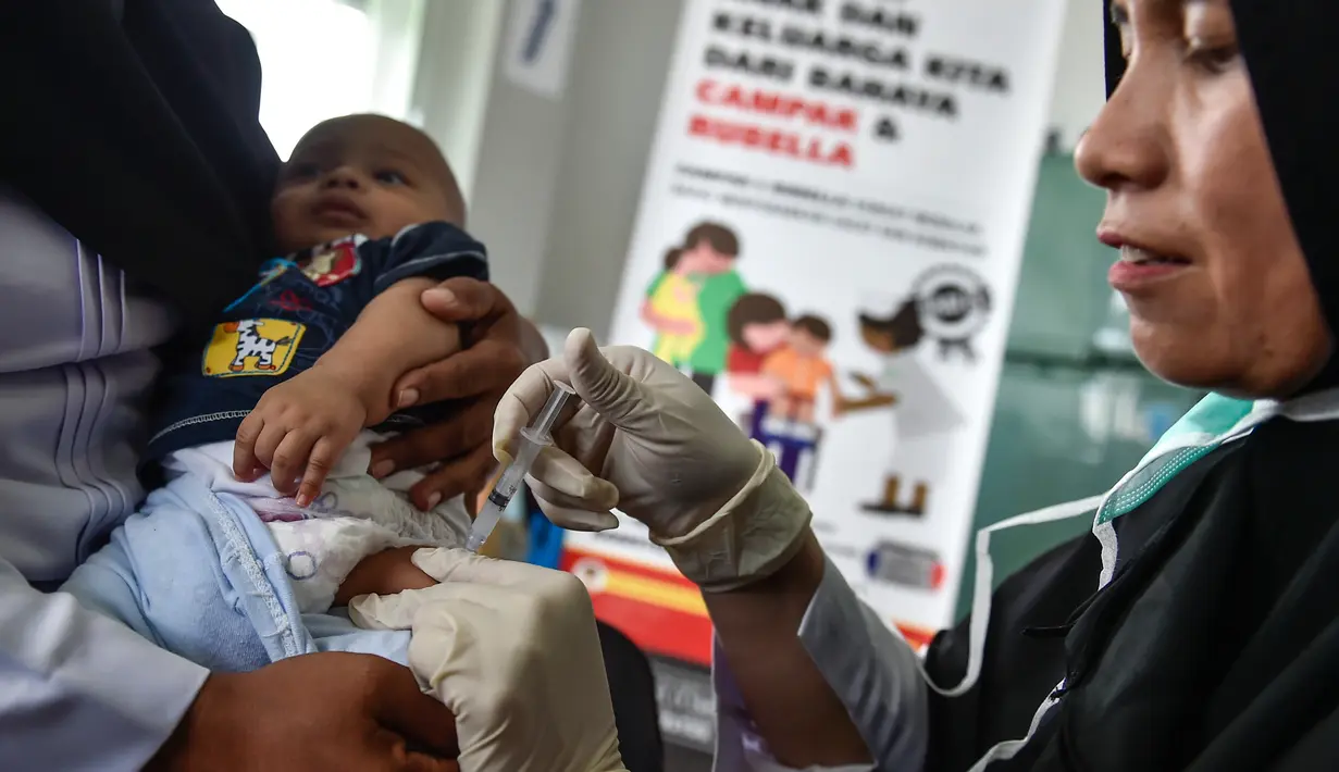 Petugas menyuntikan Vaksin Campak dan Rubella (MR) kepada bayi saat dilakukan imunisasi di sebuah puskesmas, Banda Aceh, Rabu (19/9). Pemerintah Aceh memperbolehkan penggunaan vaksin MR dengan alasan dalam kondisi darurat. (CHAIDEER MAHYUDDIN / AFP)