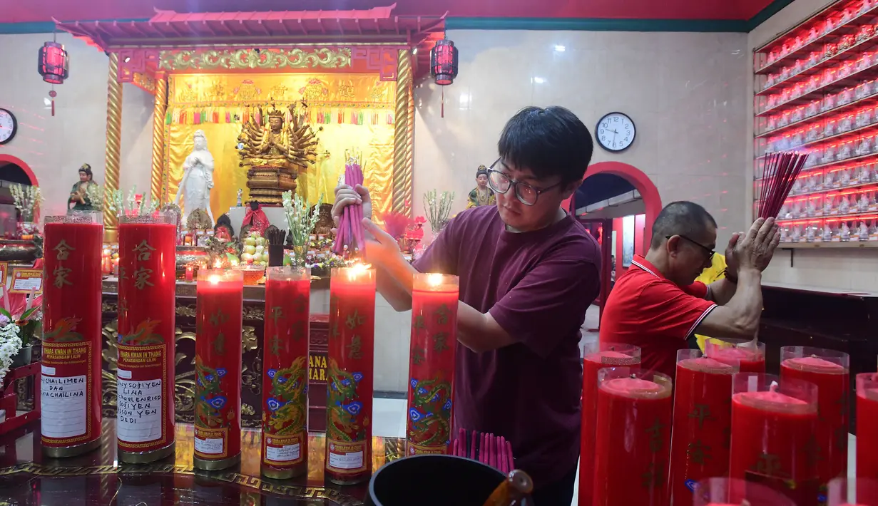 Imlek tahun ini menandai berakhirnya Tahun Ular Kayu dan dimulainya Tahun Kuda Api. Tampak dalam foto, umat Khonghucu menyalakan lilin dan melakukan sembahyang pada malam Tahun Baru Imlek di Wihara Kwan In Thang, Pondok Cabe, Tangerang Selatan, Senin (16/2/2026). (merdeka.com/Arie Basuki)