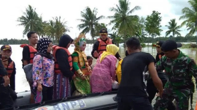 Hartina menggunakan perahu karet BPBD untuk pergi ke daerah yang tidak tergenang banjir (Fauzan/Liputan6.com)