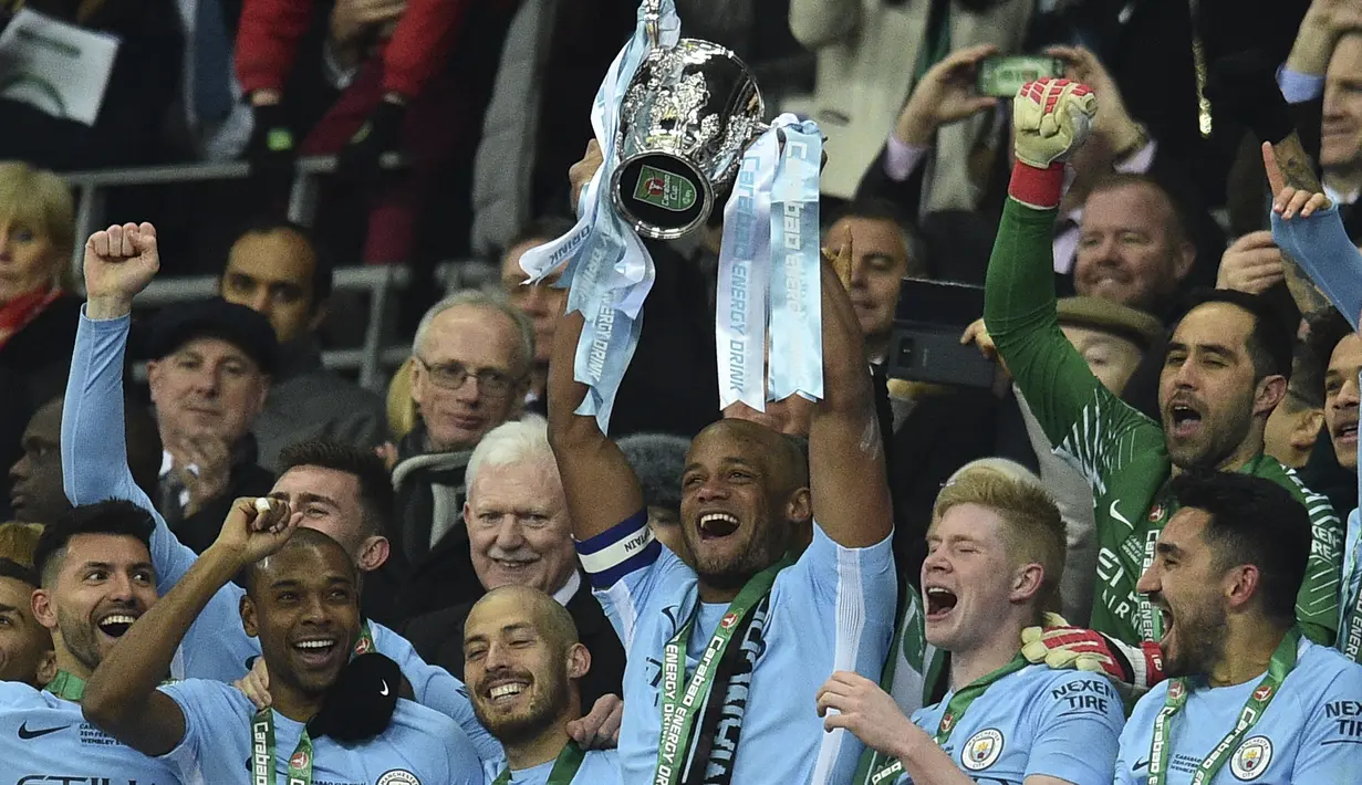 Kapten Manchester City, Vincent Kompany, mengangkat trofi Piala Liga usai mengalahkan Arsenal di Stadion Wembley, London, Minggu (25/2/2018). City menang 3-0 atas Arsenal. (AFP/Glyn Kirk)