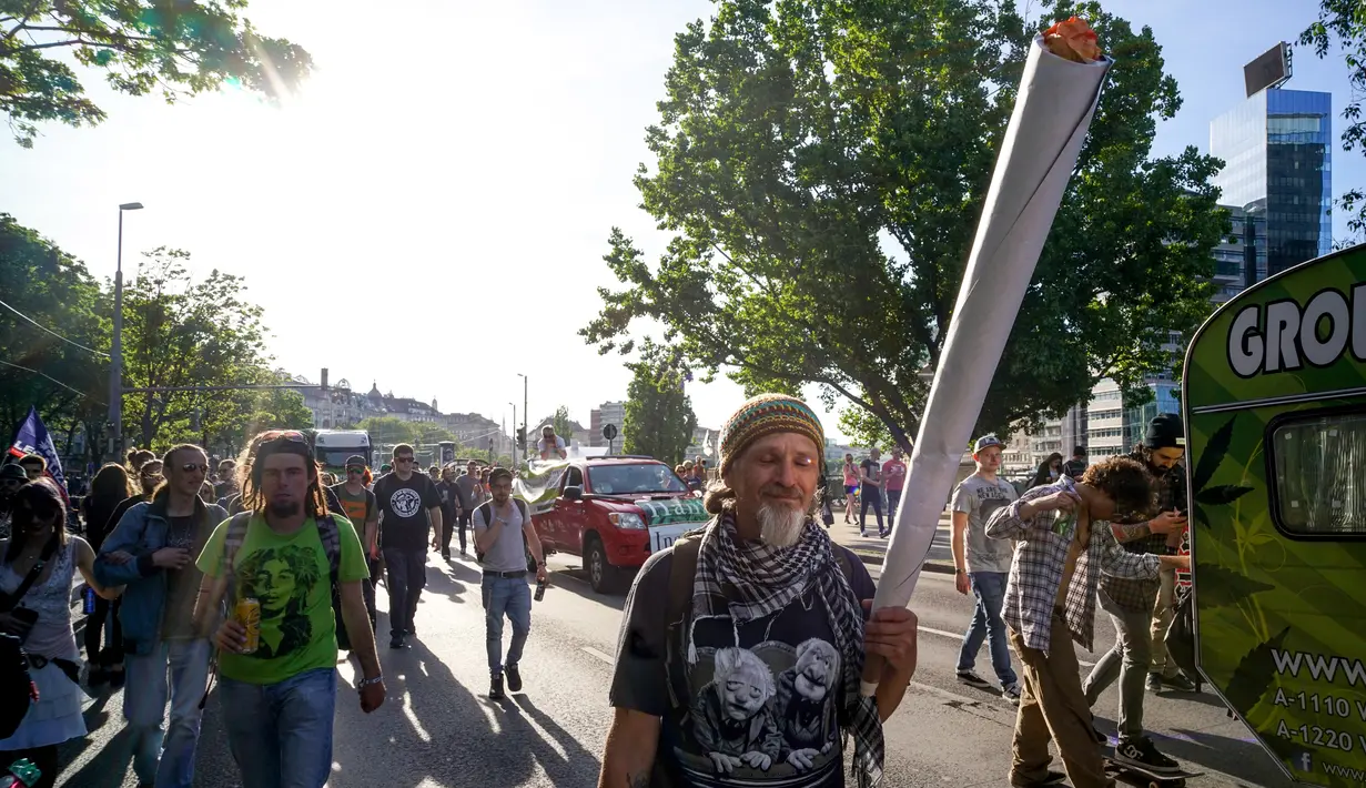 Warga membawa benda berbentuk lintingan ganja saat mengikuti Global Cannabis March di Wina, Austria, (6/5). Global Cannabis March juga menyatakan menentang perdagangan narkoba. (AFP Photo/Joe Klamar)