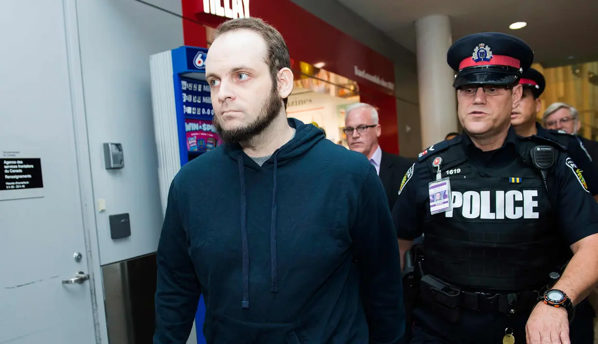 Joshua Boyle dikawal polisi setelah memberi keterangan kepada wartawan di bandara Toronto, Kanada (13/10). Boyle bersama istri dan ketiga anaknya dibebaskan oleh pasukan Pakistan dari tangan Taliban. (Nathan Denette / The Canadian Press via AP)