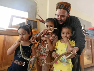 Anak-anak tampak memegang ular dengan ditemani seorang penjaga kebun binatang Salah Tolba di Giza , Mesir , 28 April 2016. kebun binatang berukuran 1.500 meter ini menjadi bahwa warga Mesir dapat menghrmati hewan. (REUTERS / Mohamed Abd El Ghany)