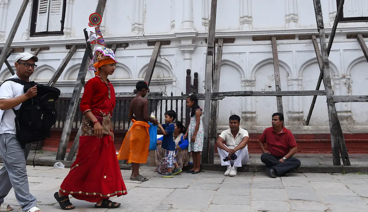 Seorang pemuda Nepal mengenakan kostum mengikuti Gai Jatra cow festival di Kathmandu, Nepal (8/8). Umat Hindu di Kathmandu merayakan Festival Sapi untuk meminta keselamatan dan kedamaian. (AFP Photo/Prakash Mathema)