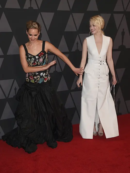 Aktris Jennifer Lawrence saat bercanda dengan Emma Stone di karpet merah saat menghadiri acara Governors Awards ke-9 di Los Angeles, California, AS (11/11). (Kevin Winter/Getty Images/AFP)