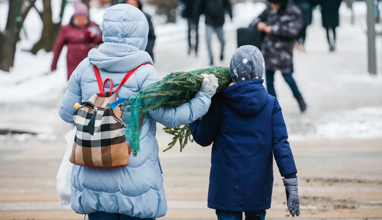 Orang-orang membawa pohon untuk perayaan Tahun Baru dari sebuah pasar di pusat kota Moskow, Rusia (27/12/2020). (Xinhua/Maxim Chernavsky)
